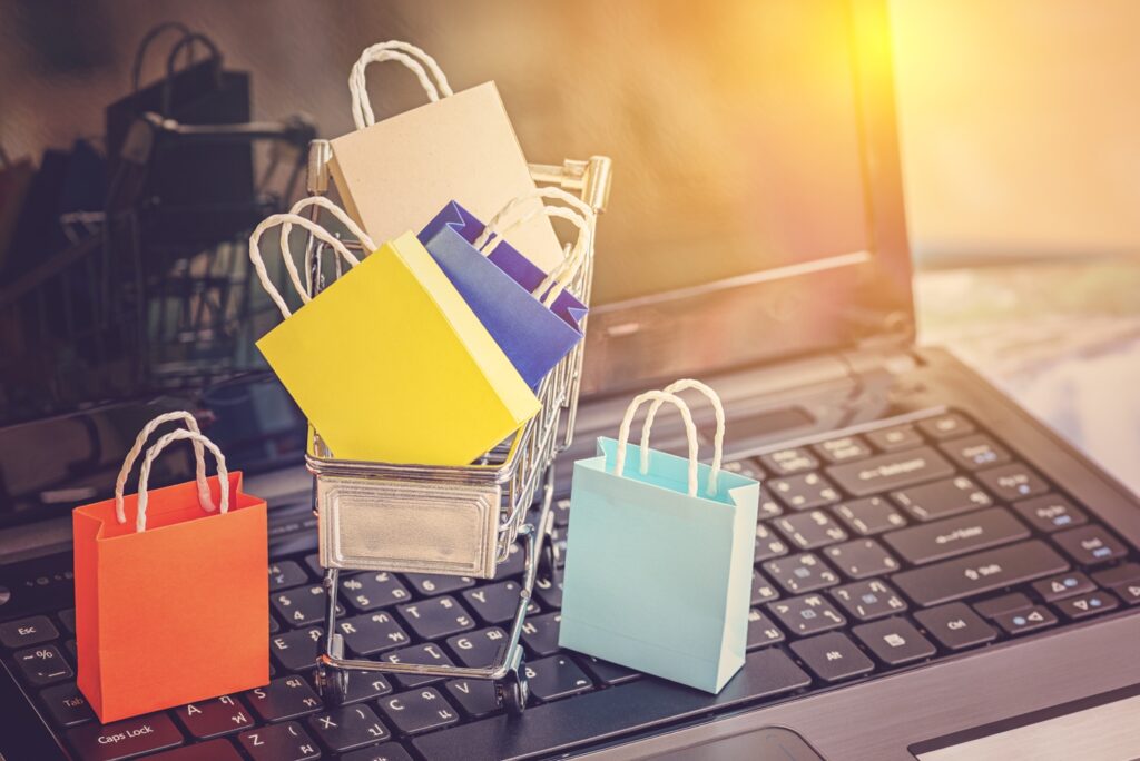 A laptop with a tiny shopping trolly and shopping bags on it, symbolising an ecommerce website.