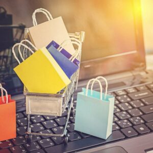 A laptop with a tiny shopping trolly and shopping bags on it, symbolising an ecommerce website.