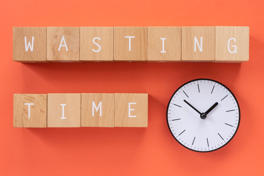 A clock, and wooden blocks spelling out the words "wasting time".